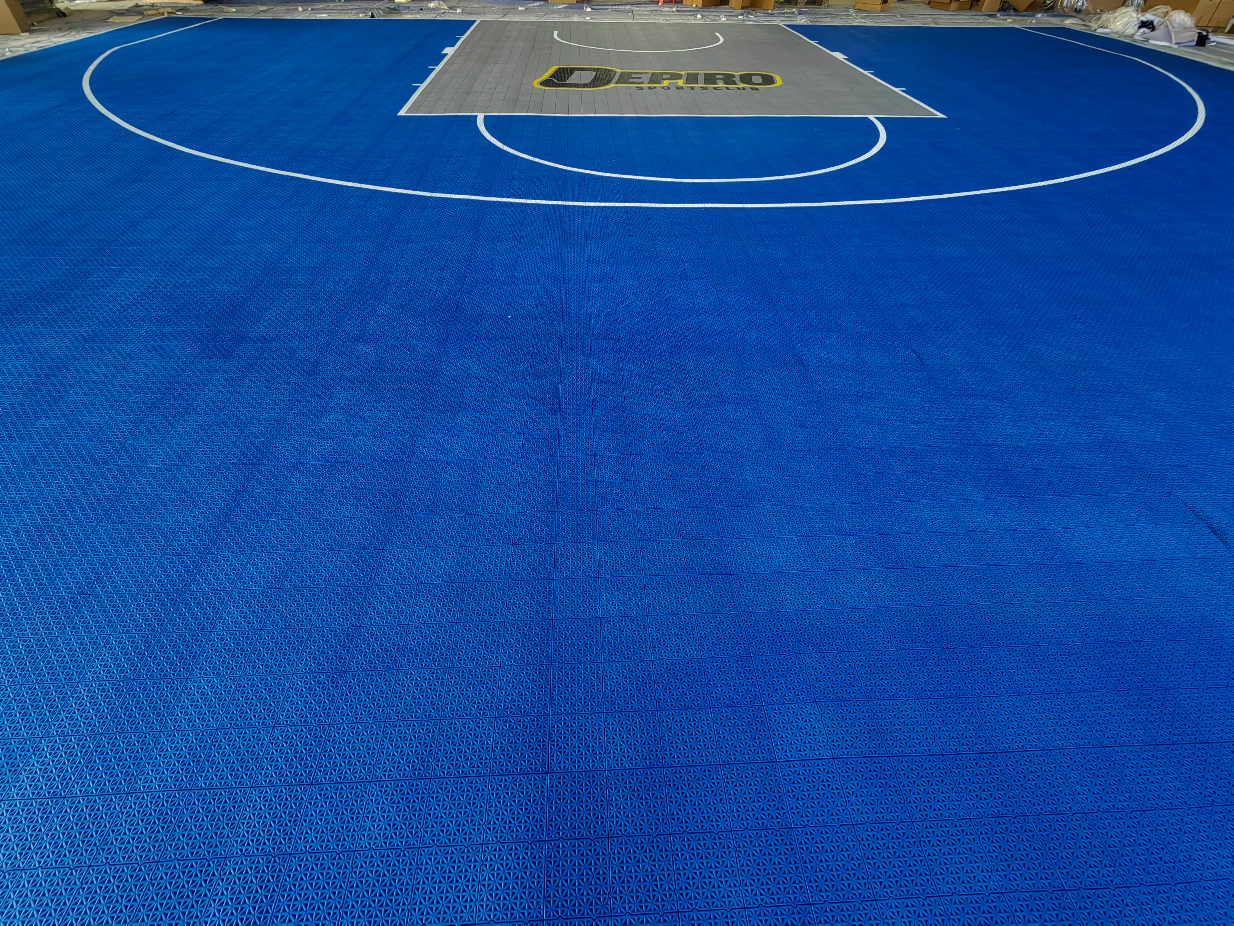 Wide warehouse view of the blue Depiro Sports basketball court