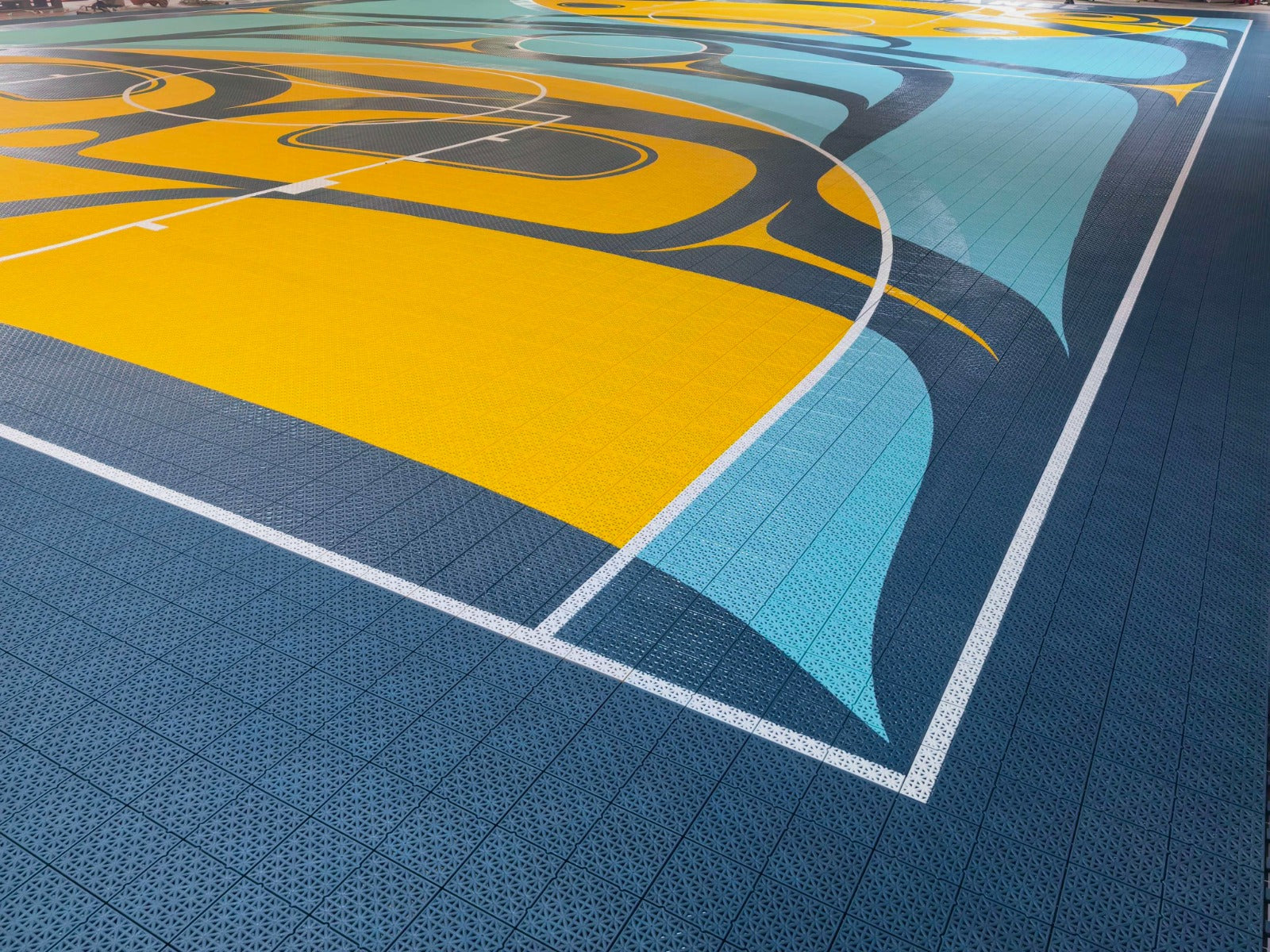 Yellow key, white court markings, and custom artwork on the Híílang Dánee court