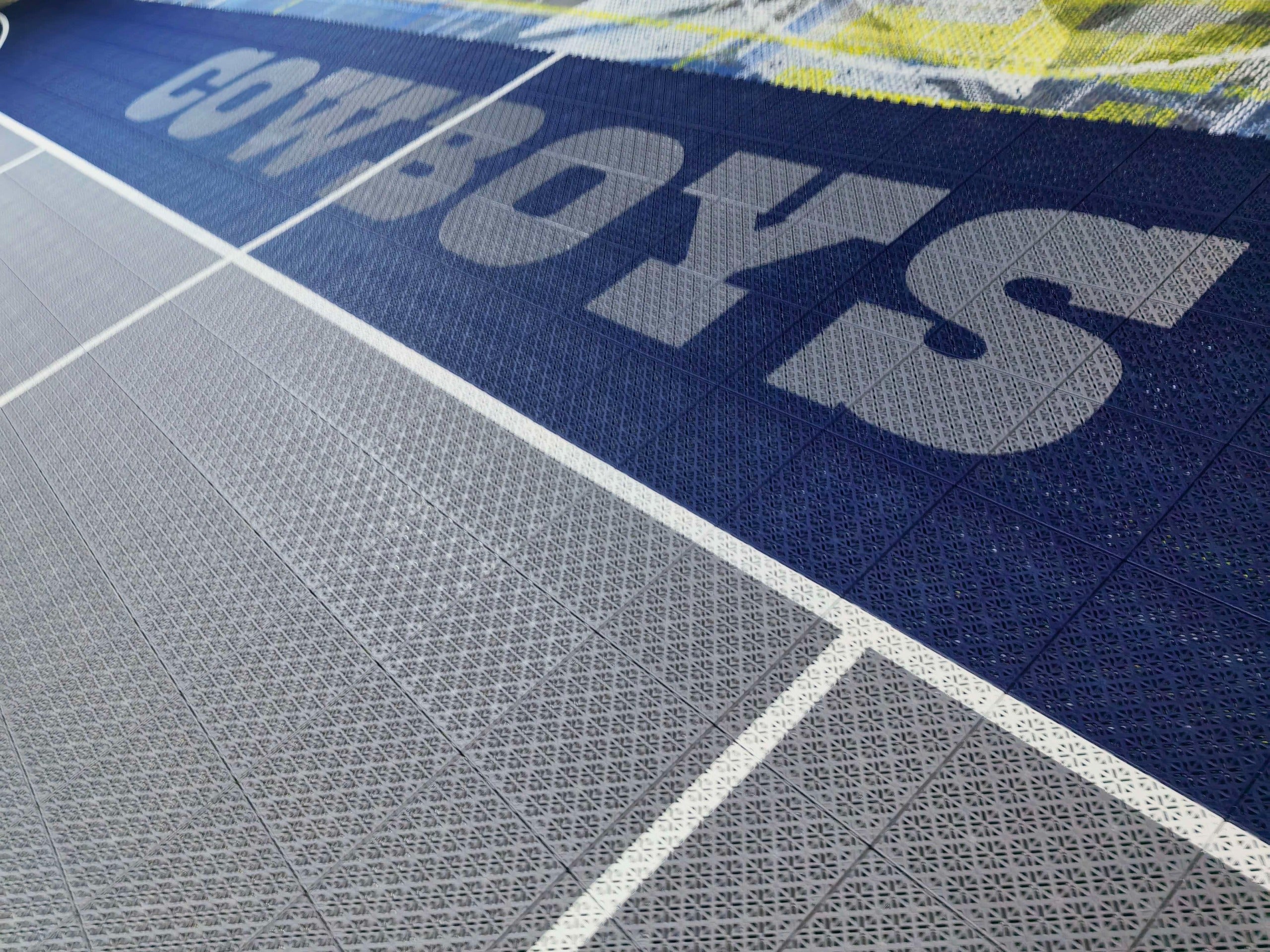 Cowboys end-zone lettering printed across navy modular court tiles