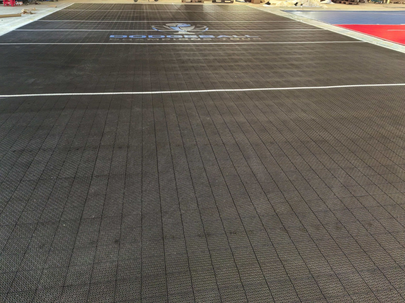 Wide warehouse view of the black Dodgeball Champions Tour court