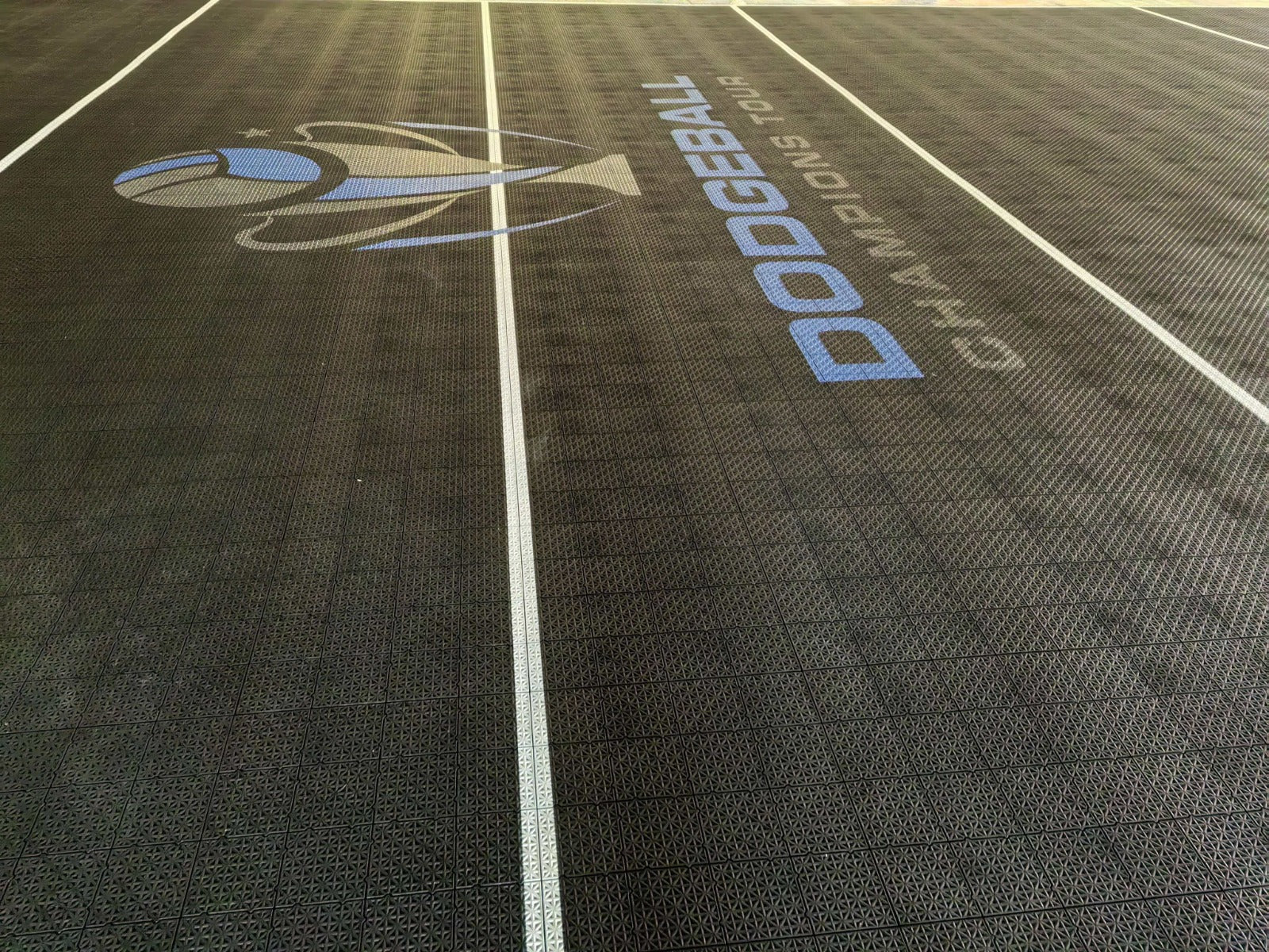 Dodgeball Champions Tour logo and white playing lines on the black court surface