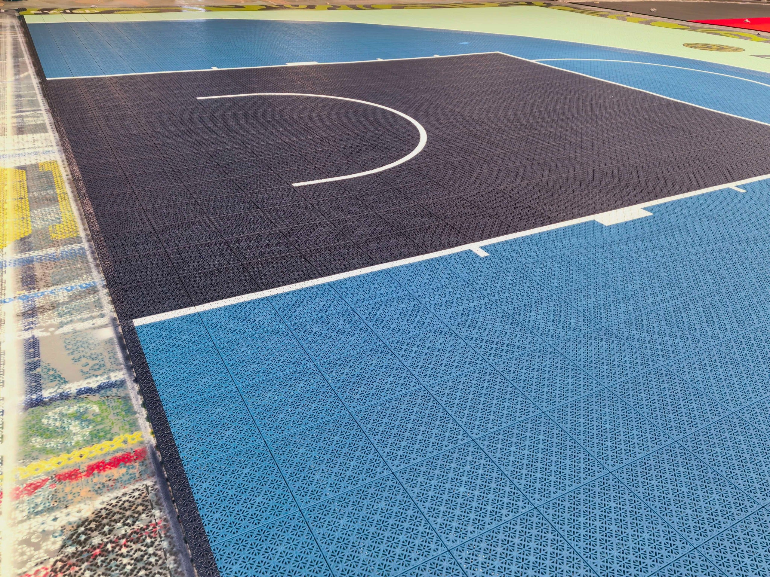 Blue key, white basketball lines, and modular Elastic tiles on the Elevate court