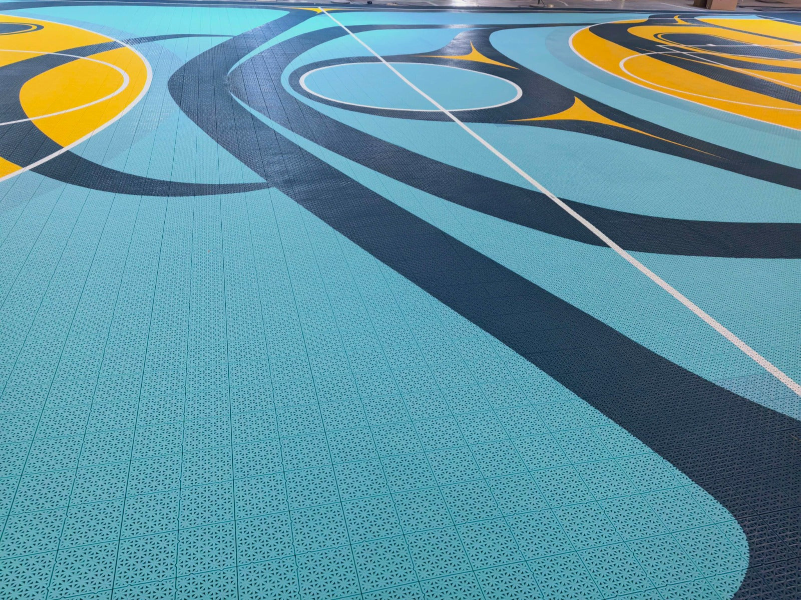 Turquoise and dark teal artwork with white court lines on the Híílang Dánee court