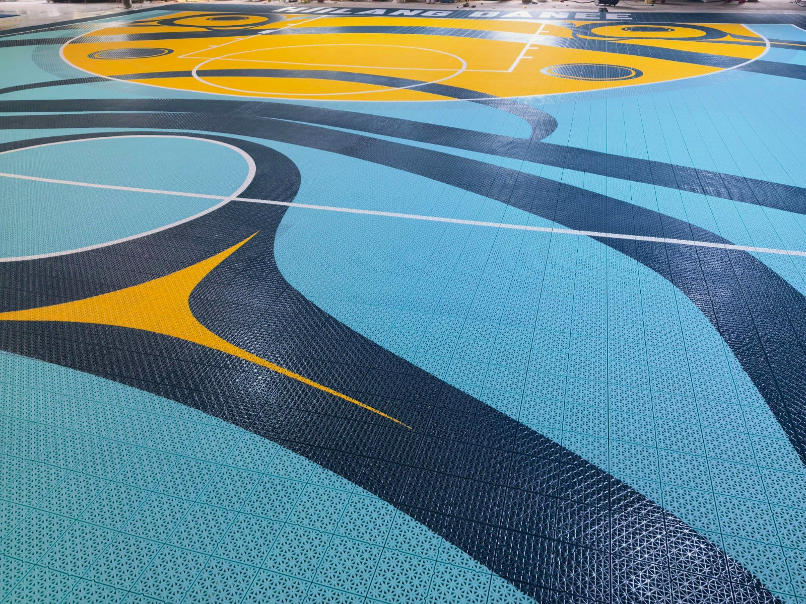 Turquoise, yellow, and dark teal artwork across the finished court surface
