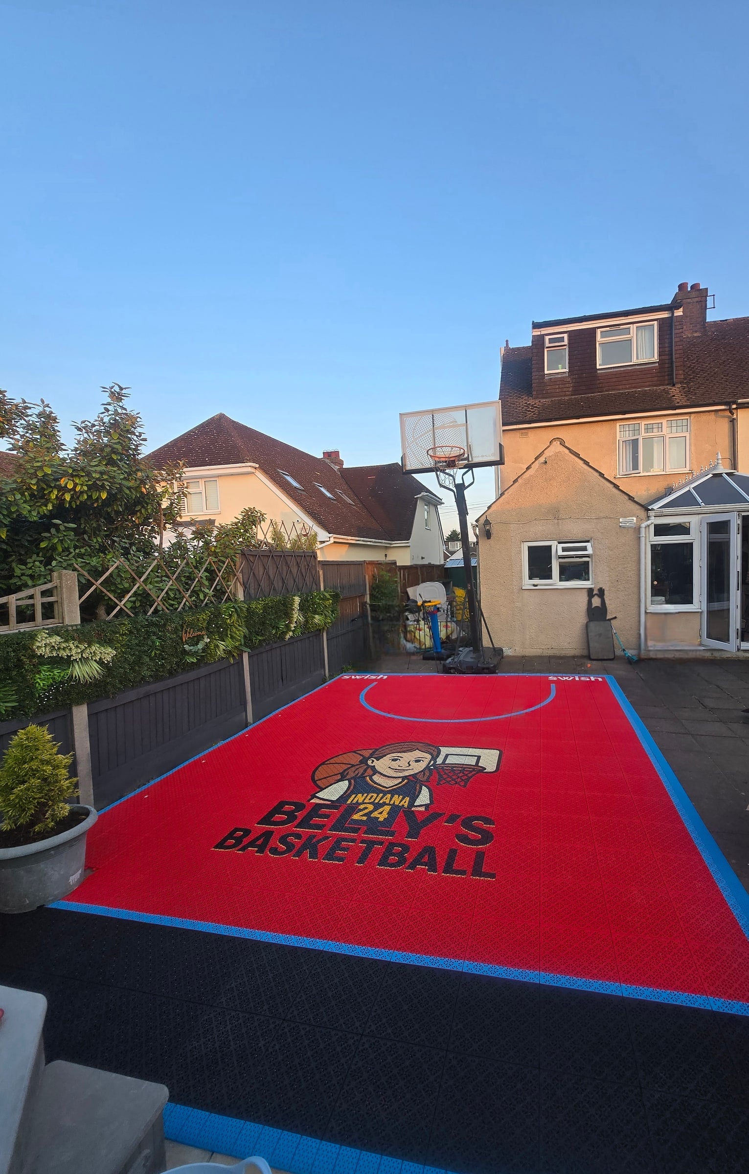 Completed red and light-blue Elastic tile backyard basketball court in Bedfordshire, project photo 1