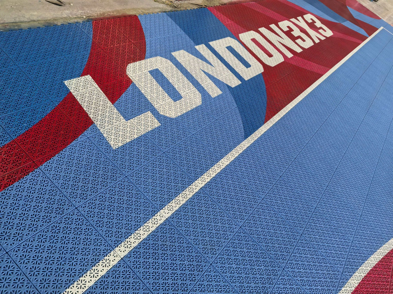 Close view of the London 3x3 lettering across red and blue modular court tiles