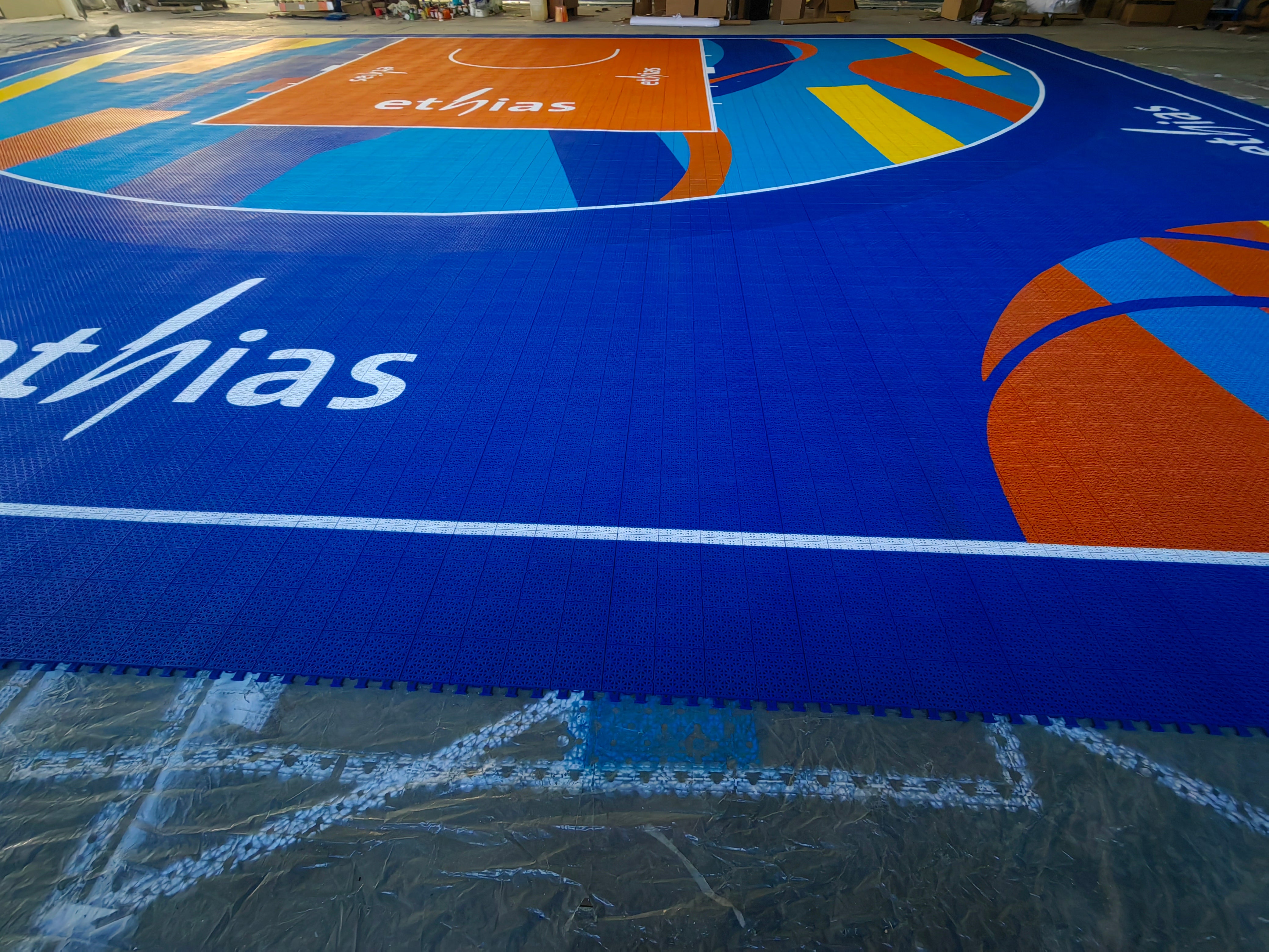 Blue Ethias border artwork and orange key across the warehouse-assembled court