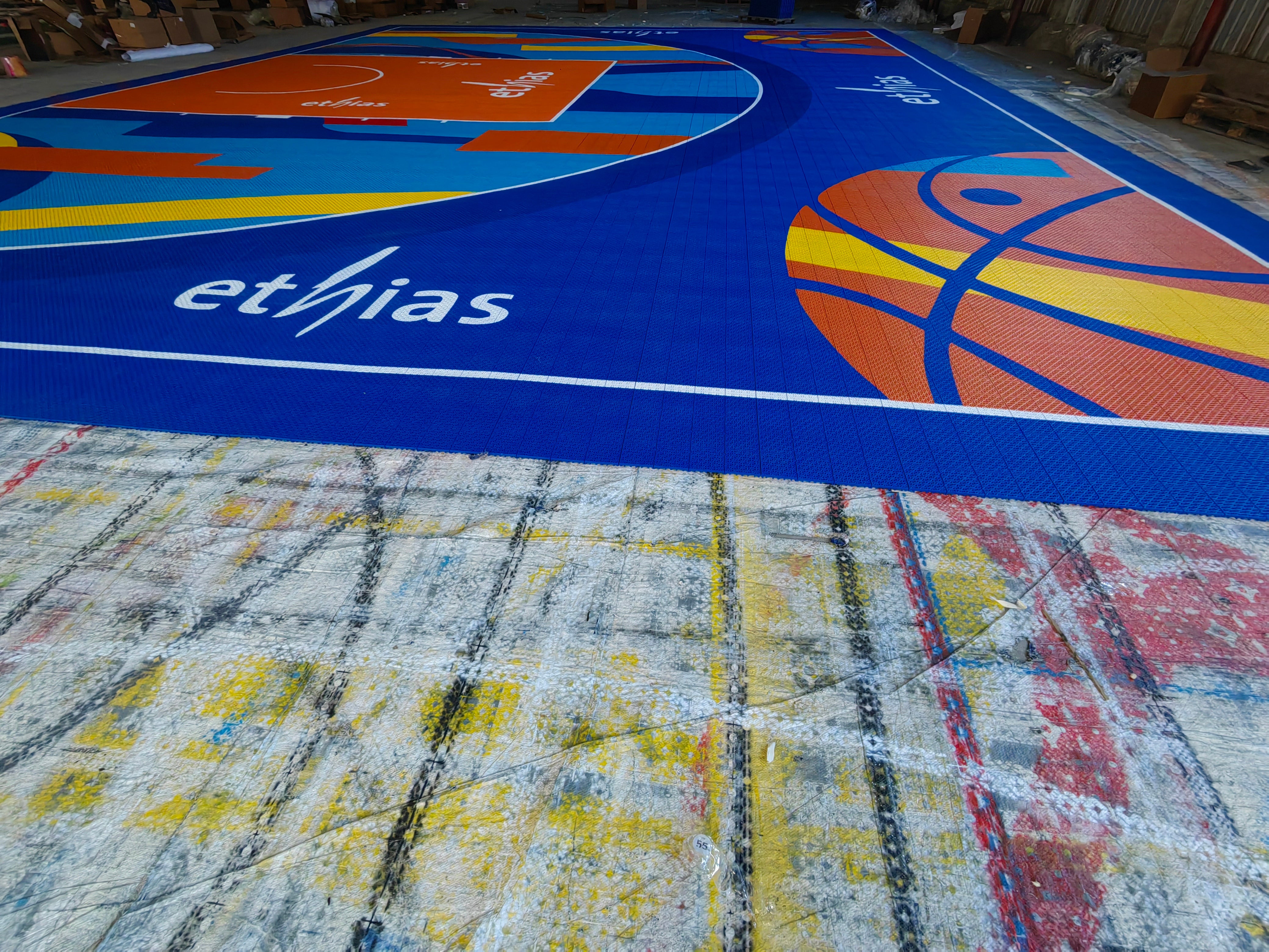 Wide view of the blue, orange, and turquoise Ethias court assembled in the warehouse