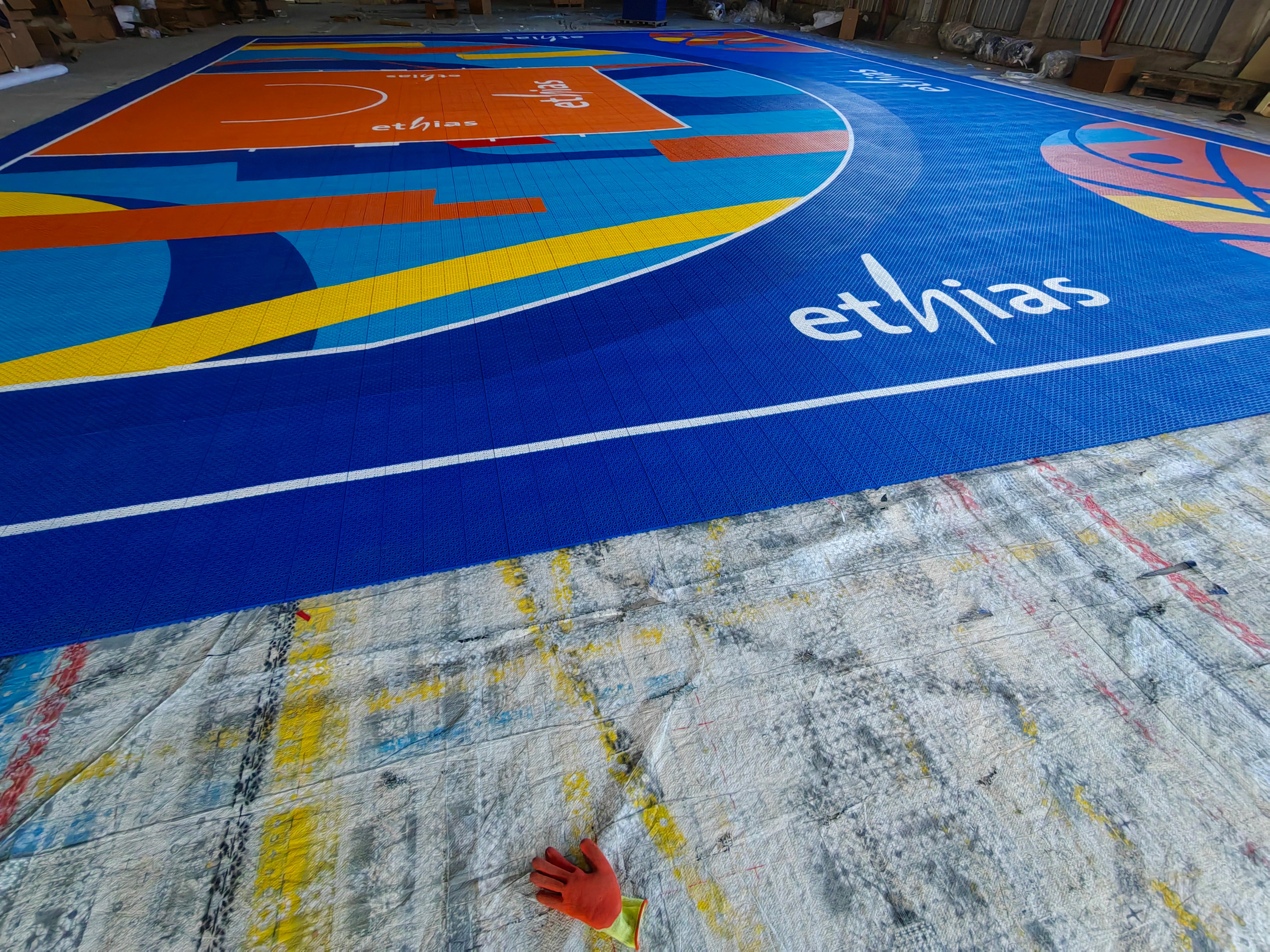 Ethias branding beside the custom court graphics and white playing line